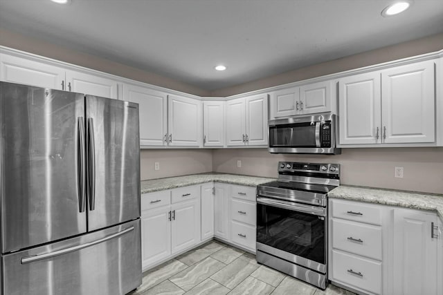 kitchen with light stone countertops, white cabinetry, and appliances with stainless steel finishes