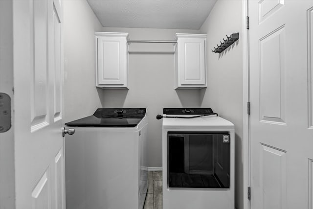 laundry room featuring cabinets, washer and dryer, and a textured ceiling