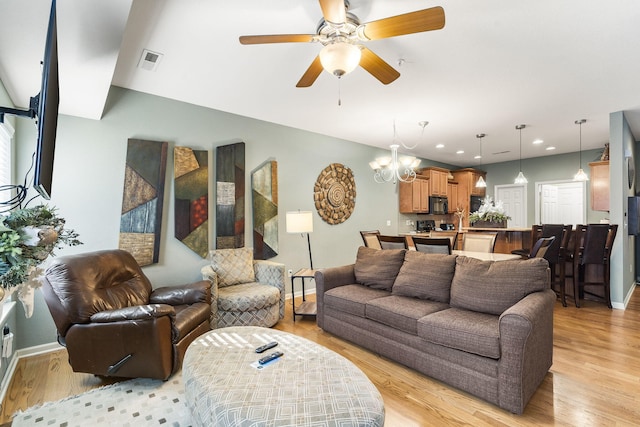 living room with ceiling fan with notable chandelier and light hardwood / wood-style floors