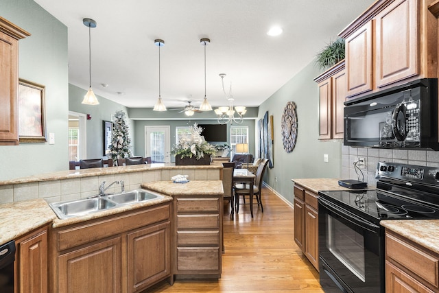 kitchen with sink, light hardwood / wood-style flooring, pendant lighting, decorative backsplash, and black appliances