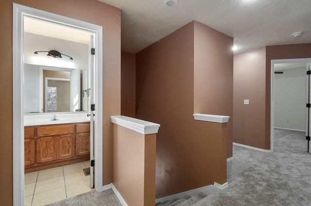 hallway featuring light carpet and sink