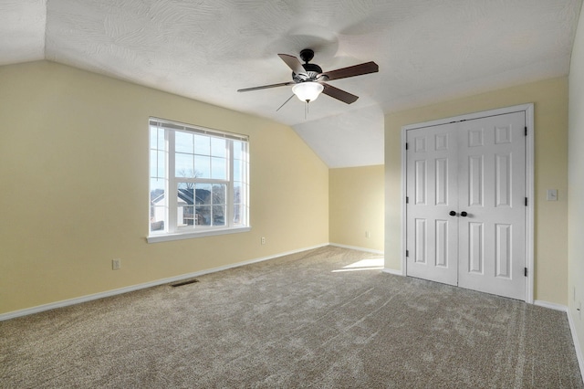 additional living space with ceiling fan, lofted ceiling, carpet flooring, and a textured ceiling