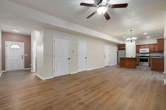 unfurnished living room with sink, ceiling fan with notable chandelier, and dark hardwood / wood-style flooring