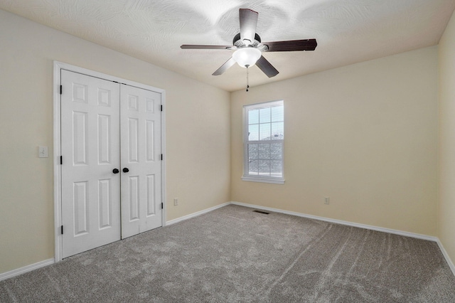 unfurnished bedroom featuring carpet floors, a closet, and ceiling fan