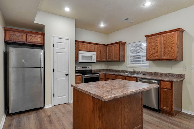 kitchen featuring stainless steel appliances, sink, a center island, and light hardwood / wood-style floors