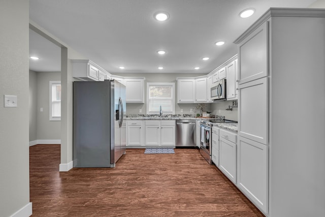 kitchen with dark wood-type flooring, sink, white cabinetry, light stone counters, and appliances with stainless steel finishes