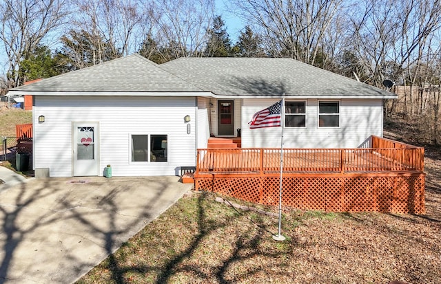 view of front of home with a deck, roof with shingles, and a patio area