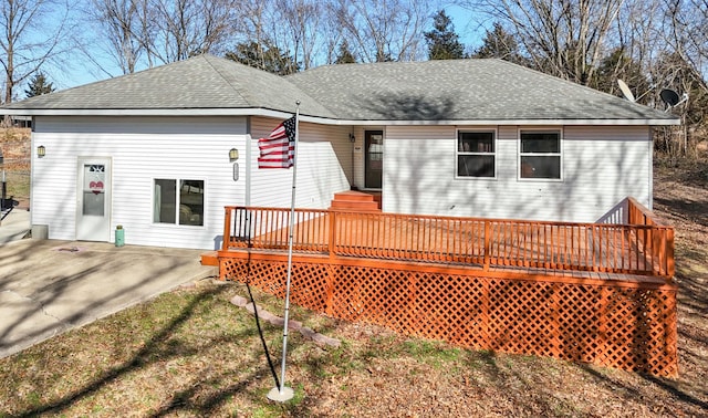 back of house with a shingled roof, a patio, and a deck