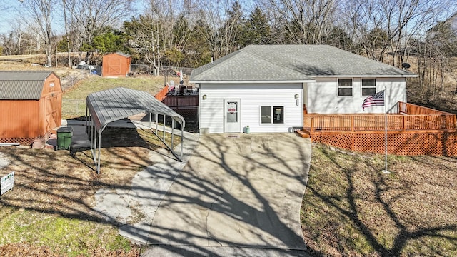 rear view of house featuring an outbuilding, a shed, a shingled roof, and a wooden deck