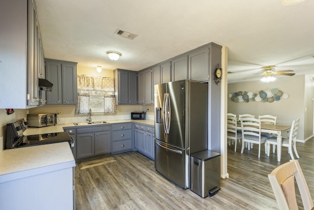 kitchen with stainless steel fridge, visible vents, light countertops, black range with electric cooktop, and a sink