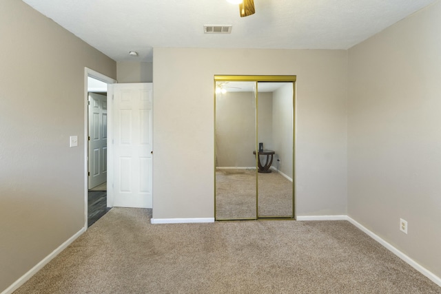 unfurnished bedroom featuring baseboards, carpet, visible vents, and a closet