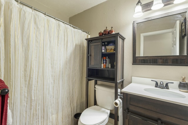 bathroom with toilet, a textured wall, a shower with shower curtain, and vanity