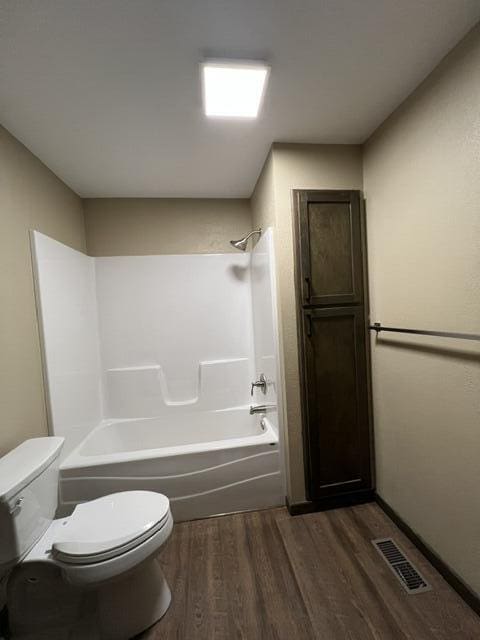 bathroom with hardwood / wood-style flooring, toilet, and shower / bathing tub combination