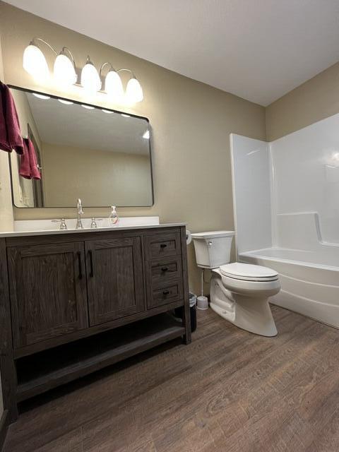 full bathroom featuring vanity, tub / shower combination, hardwood / wood-style floors, and toilet