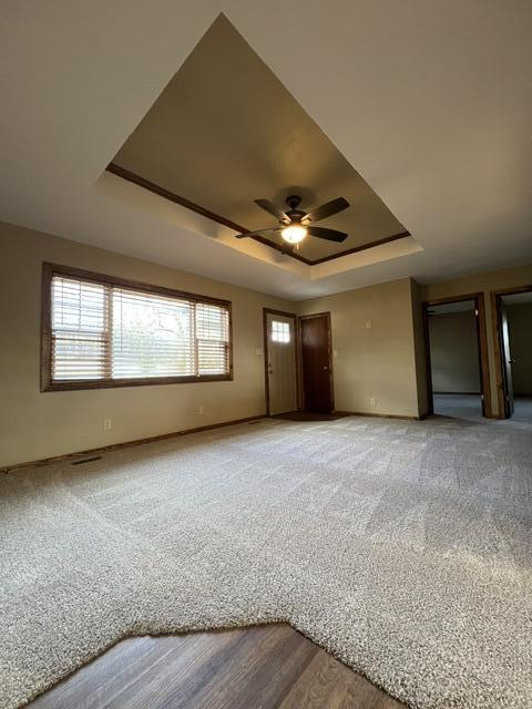 unfurnished bedroom with a raised ceiling and carpet flooring