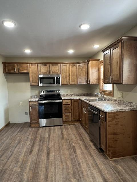 kitchen featuring light stone counters, sink, dark wood-type flooring, and appliances with stainless steel finishes