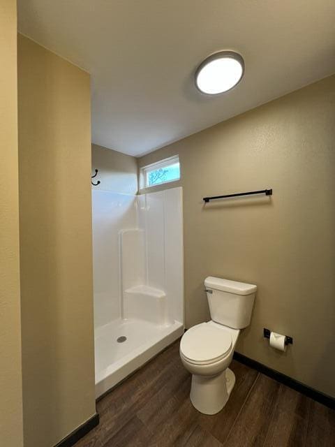 bathroom with wood-type flooring, a shower, and toilet