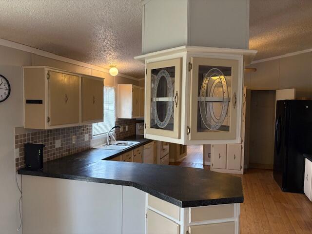 kitchen with black refrigerator, sink, kitchen peninsula, crown molding, and a textured ceiling