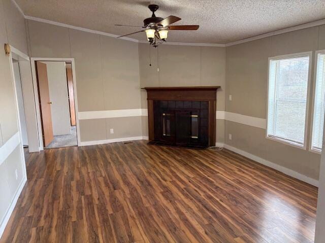 unfurnished living room with crown molding, a healthy amount of sunlight, dark hardwood / wood-style flooring, and a tile fireplace