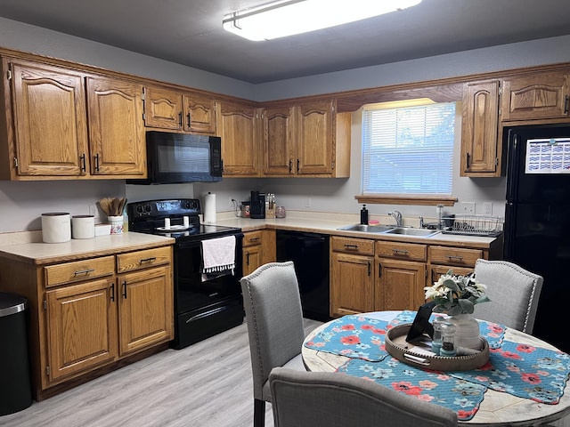 kitchen with light hardwood / wood-style floors, sink, and black appliances