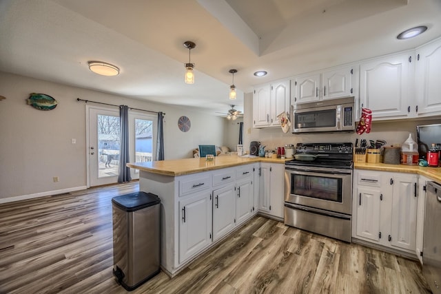 kitchen featuring pendant lighting, hardwood / wood-style flooring, stainless steel appliances, white cabinets, and kitchen peninsula