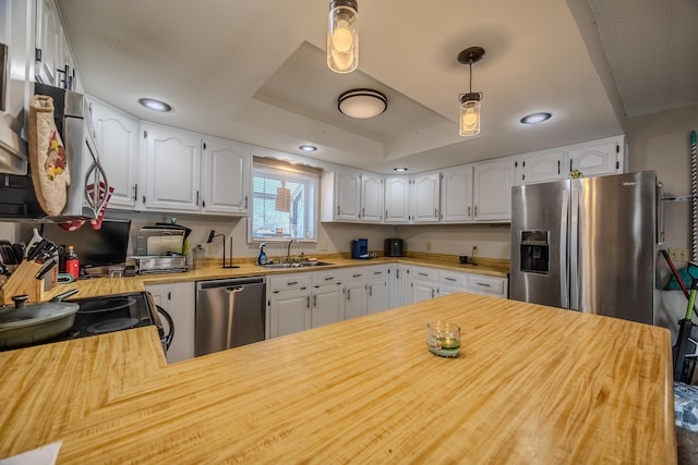 kitchen featuring white cabinetry, stainless steel appliances, kitchen peninsula, and a raised ceiling