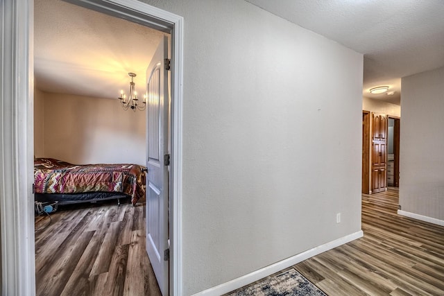 hall with hardwood / wood-style floors, a notable chandelier, and a textured ceiling