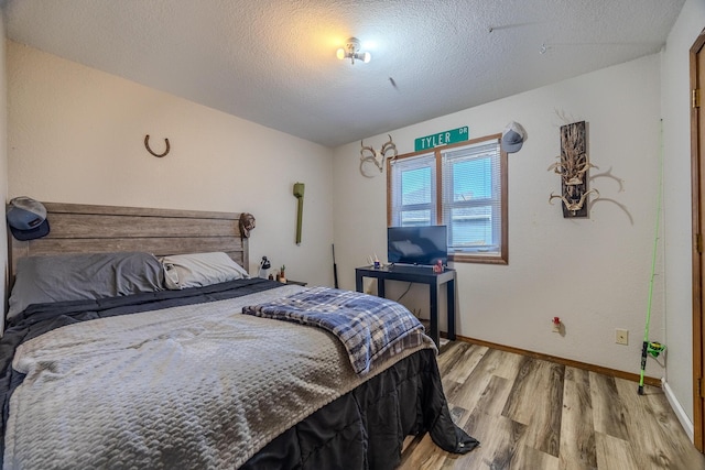 bedroom with a textured ceiling and light hardwood / wood-style flooring