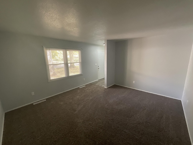 carpeted empty room with a textured ceiling