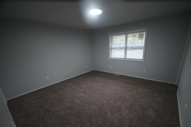 unfurnished room featuring dark colored carpet