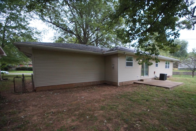 rear view of house featuring central AC unit, a lawn, and a patio