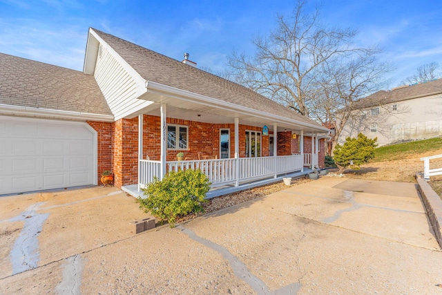 view of front of house featuring an attached garage, covered porch, brick siding, a shingled roof, and driveway