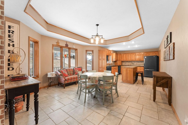 dining space with a raised ceiling and a chandelier