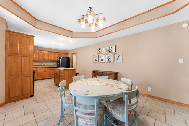 dining area with ornamental molding, a tray ceiling, baseboards, and an inviting chandelier