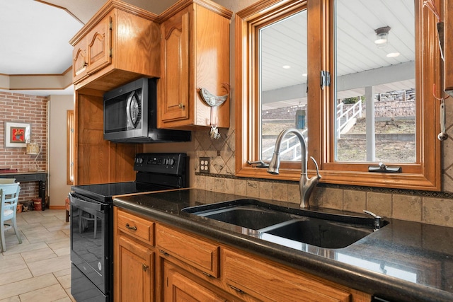 kitchen with brown cabinets, tasteful backsplash, dark countertops, a sink, and black range with electric cooktop