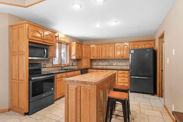 kitchen with butcher block countertops, a sink, a kitchen island, black appliances, and tasteful backsplash