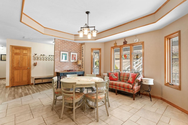 dining area featuring baseboards, crown molding, a tray ceiling, and a notable chandelier