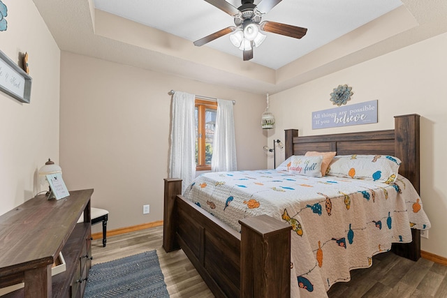 bedroom featuring ceiling fan, a tray ceiling, and hardwood / wood-style floors