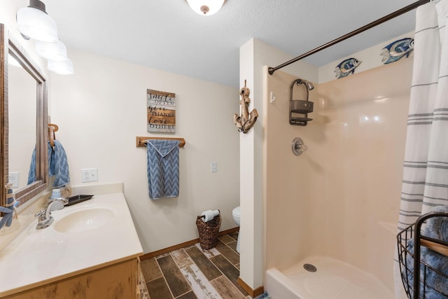 bathroom with vanity, curtained shower, a textured ceiling, and toilet