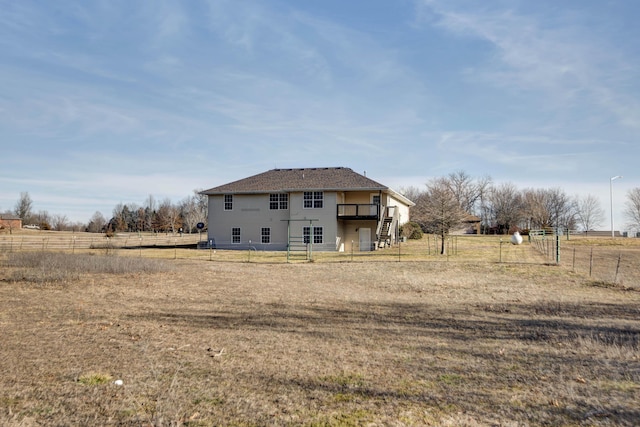 rear view of house with a wooden deck, a yard, and a rural view