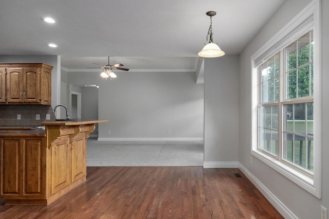 kitchen featuring pendant lighting, sink, dark wood-type flooring, ceiling fan, and tasteful backsplash