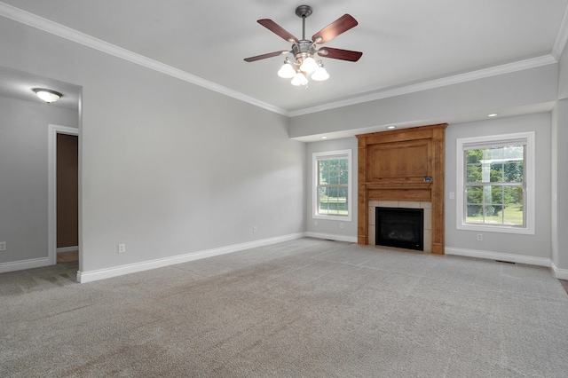 unfurnished living room with ceiling fan, ornamental molding, a tile fireplace, and light carpet