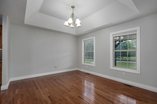 spare room with a notable chandelier, dark hardwood / wood-style flooring, and a tray ceiling