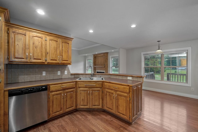 kitchen featuring sink, dishwasher, hanging light fixtures, backsplash, and kitchen peninsula