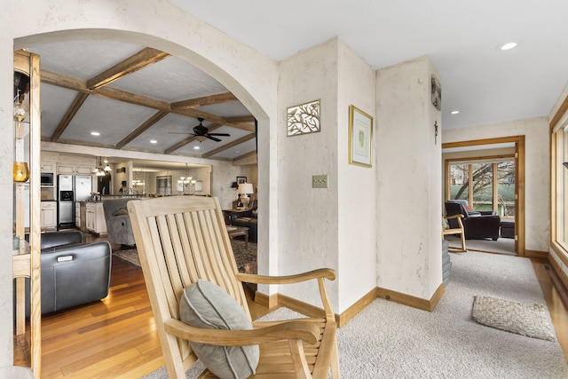 interior space featuring beamed ceiling, ceiling fan, coffered ceiling, and light hardwood / wood-style floors