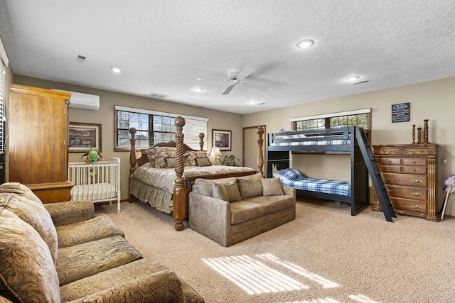 carpeted bedroom with a wall mounted AC, a textured ceiling, and ceiling fan