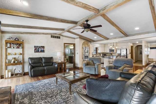 living room featuring vaulted ceiling with beams, ceiling fan, and light wood-type flooring