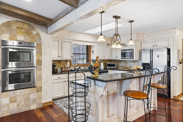 kitchen with a breakfast bar area, hanging light fixtures, stainless steel appliances, dark hardwood / wood-style floors, and a center island