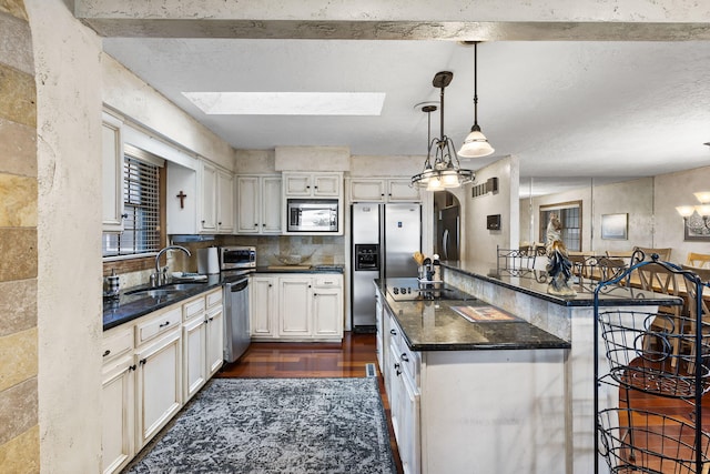 kitchen featuring pendant lighting, sink, a breakfast bar, appliances with stainless steel finishes, and white cabinetry