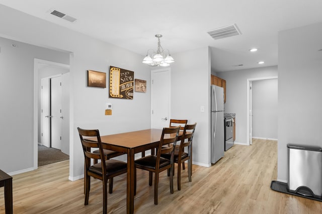 dining space with a chandelier and light hardwood / wood-style floors